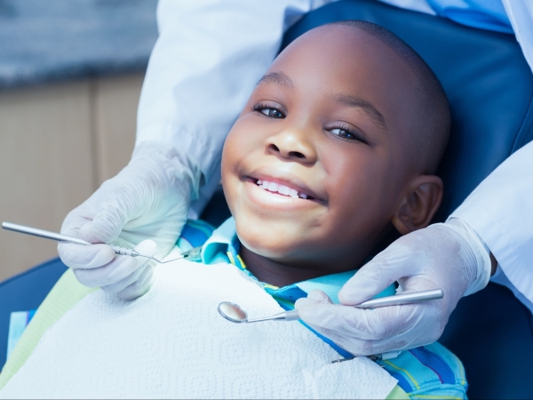 young boy smiling as the dentist waits to examine his mouth with dental tools